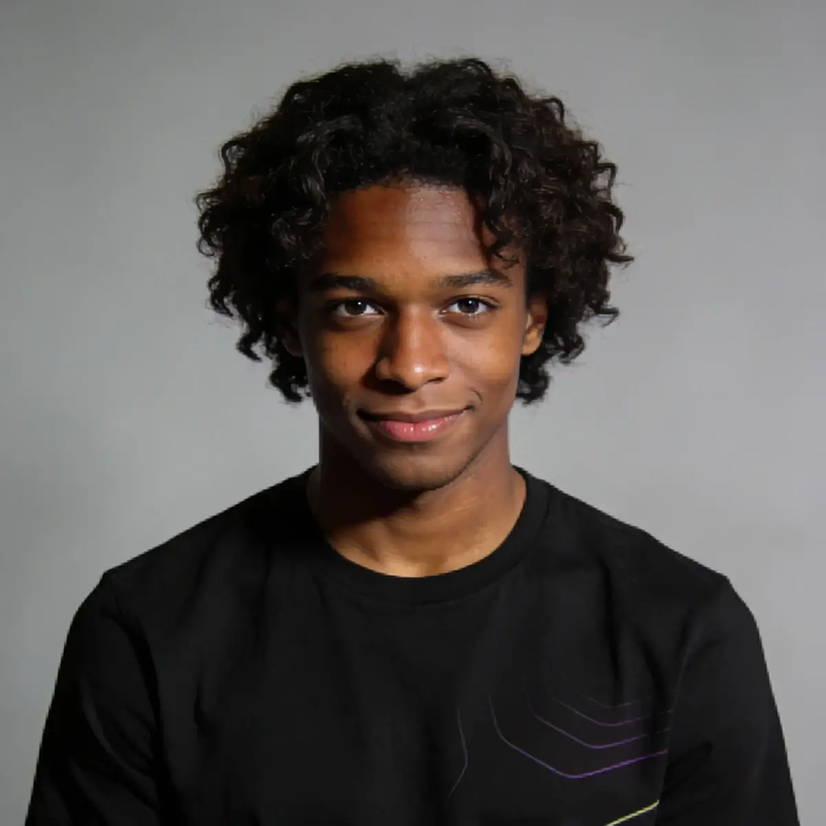 Portrait of a man with curly hair wearing dark clothing against a neutral background
