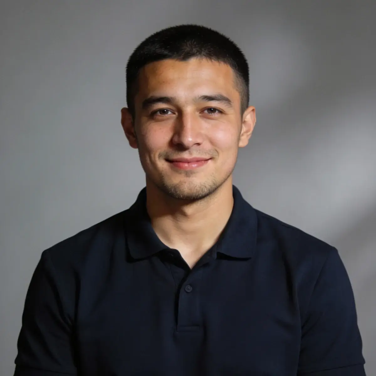 Portrait of a man in a dark-colored shirt, smiling softly.