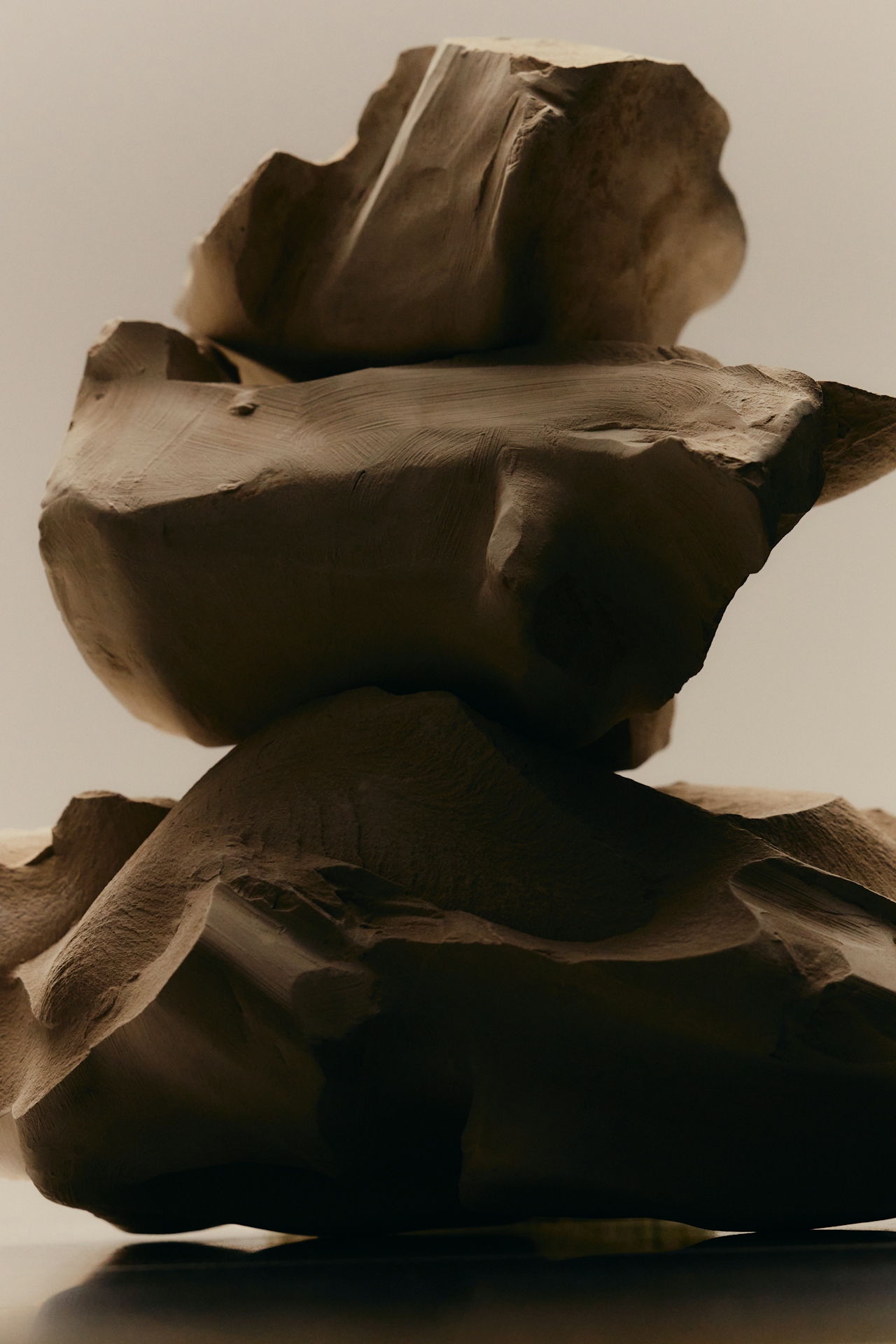 Close-up of abstract, rough-textured brown stone or clay sculpture with layered, uneven surfaces.