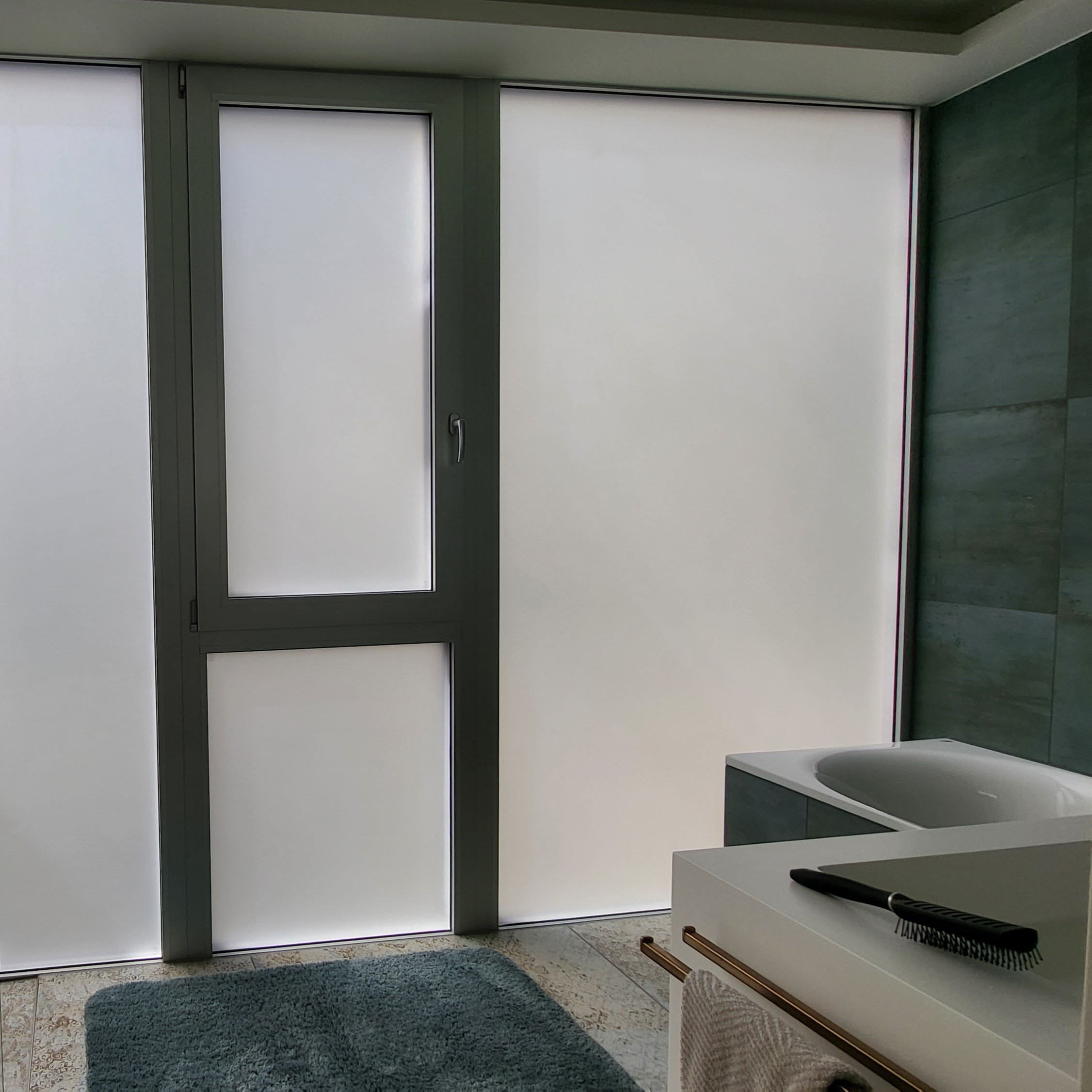 Bad mit mattem Fenster, blauer Matte, weissem Waschtisch mit Kamm und weissem Handtuch.