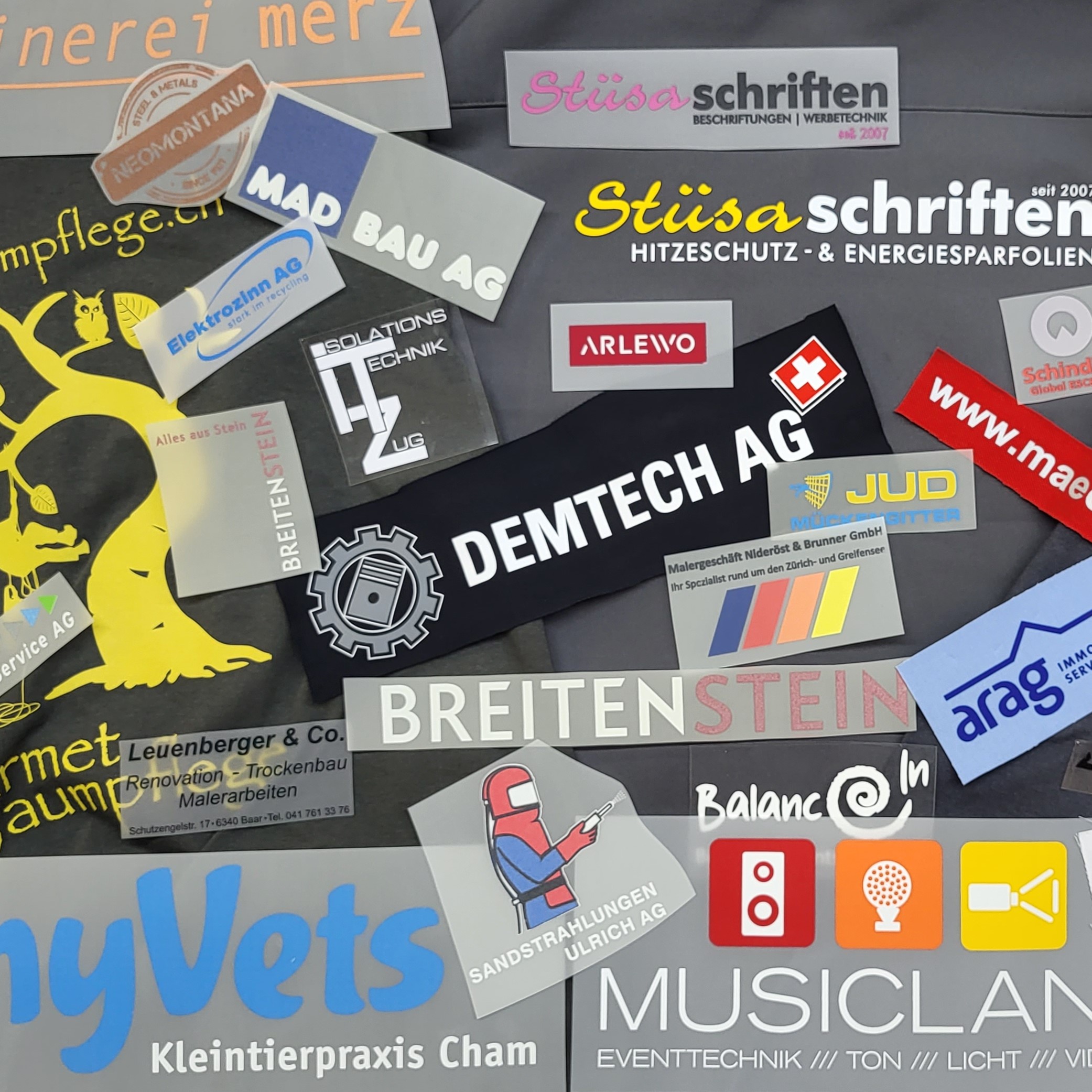 Vielfältige Firmenschilder und Logos für Handwerk, Technik, Praxis und Eventtechnik auf dunklem Hintergrund.