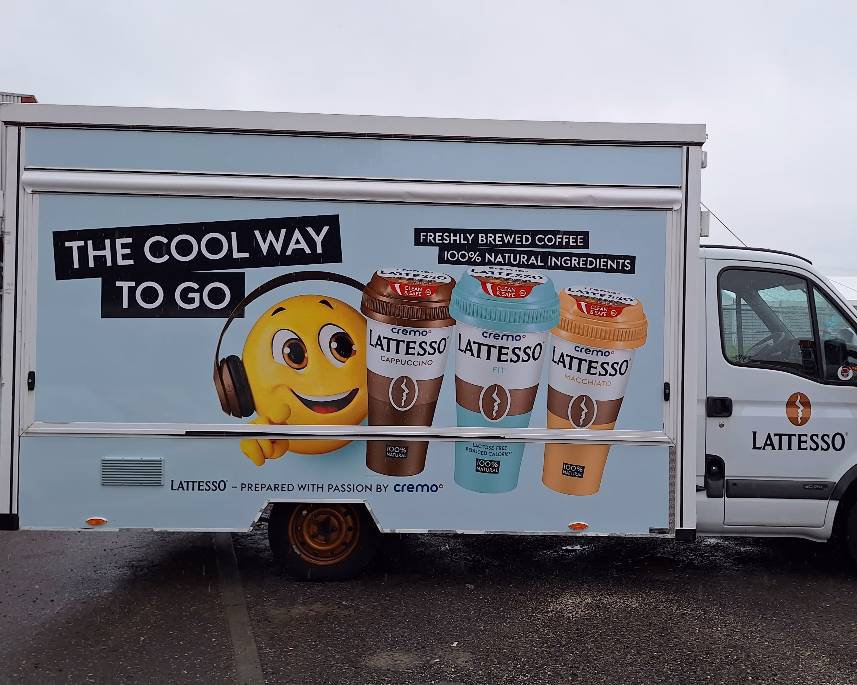 Werbelaster auf Transporter für Lattesso Kaffee mit Emoji und drei Kaffeebechern.