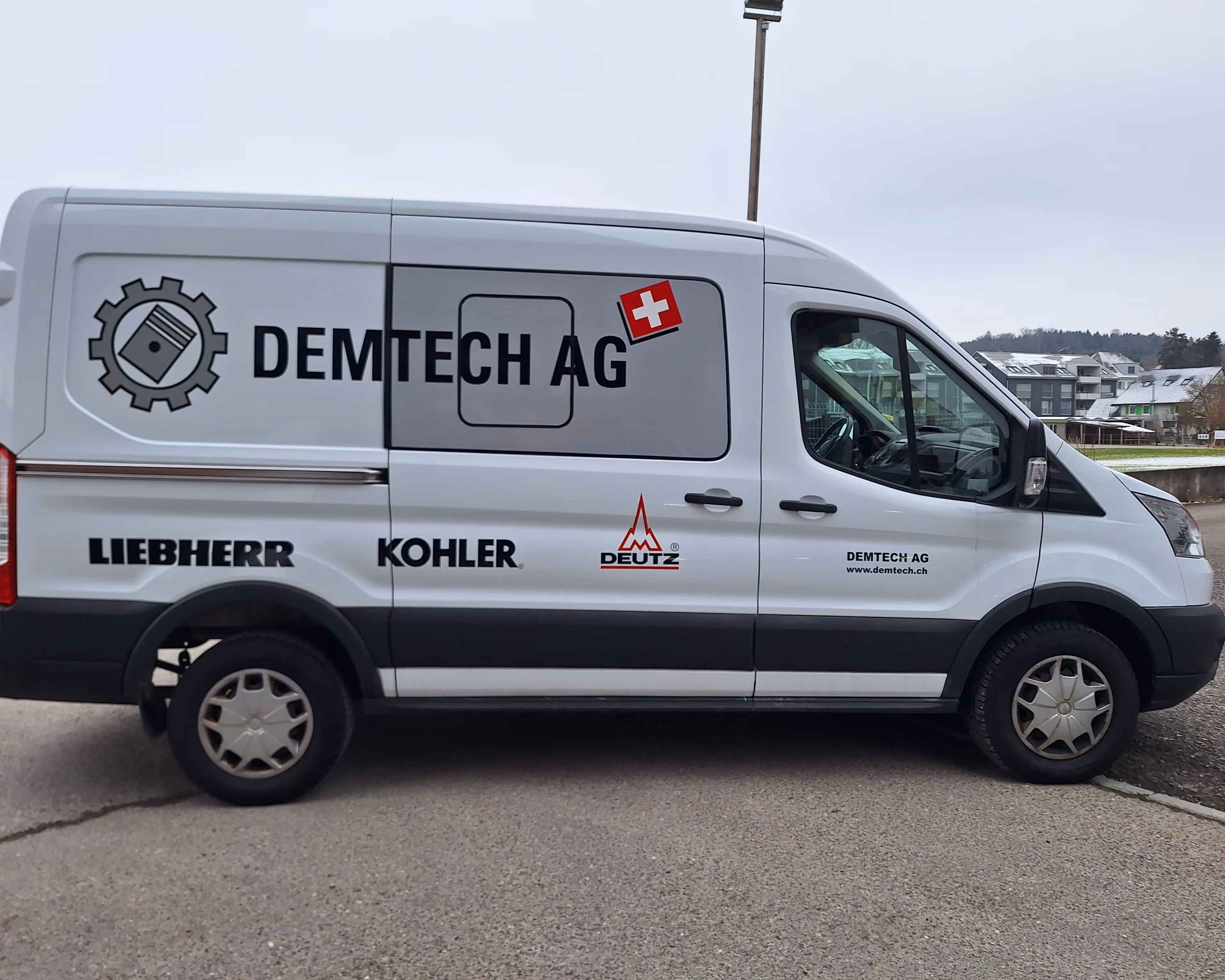 Weisser Lieferwagen mit Aufschrift Demtech AG, Schweizer Flagge und Logos von Liebherr, Kohler, Deutz.