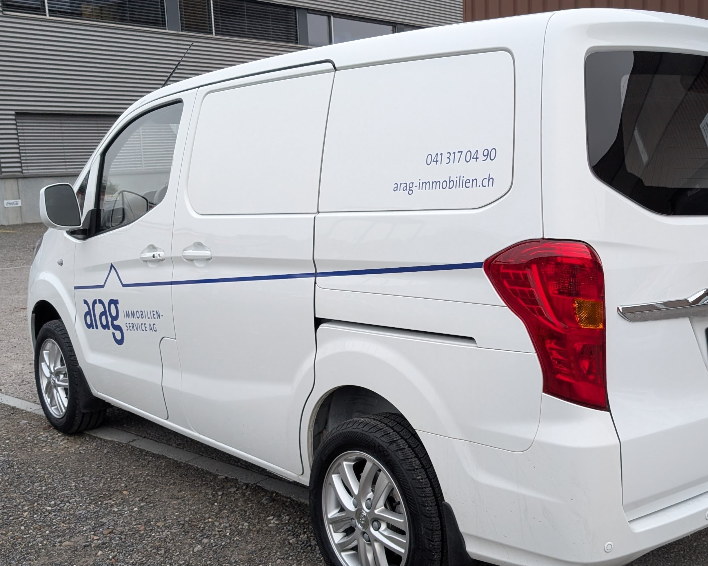 Weisser Transporter mit der Aufschrift "arag Immobilien Service AG" und Kontaktdaten auf der Seite.