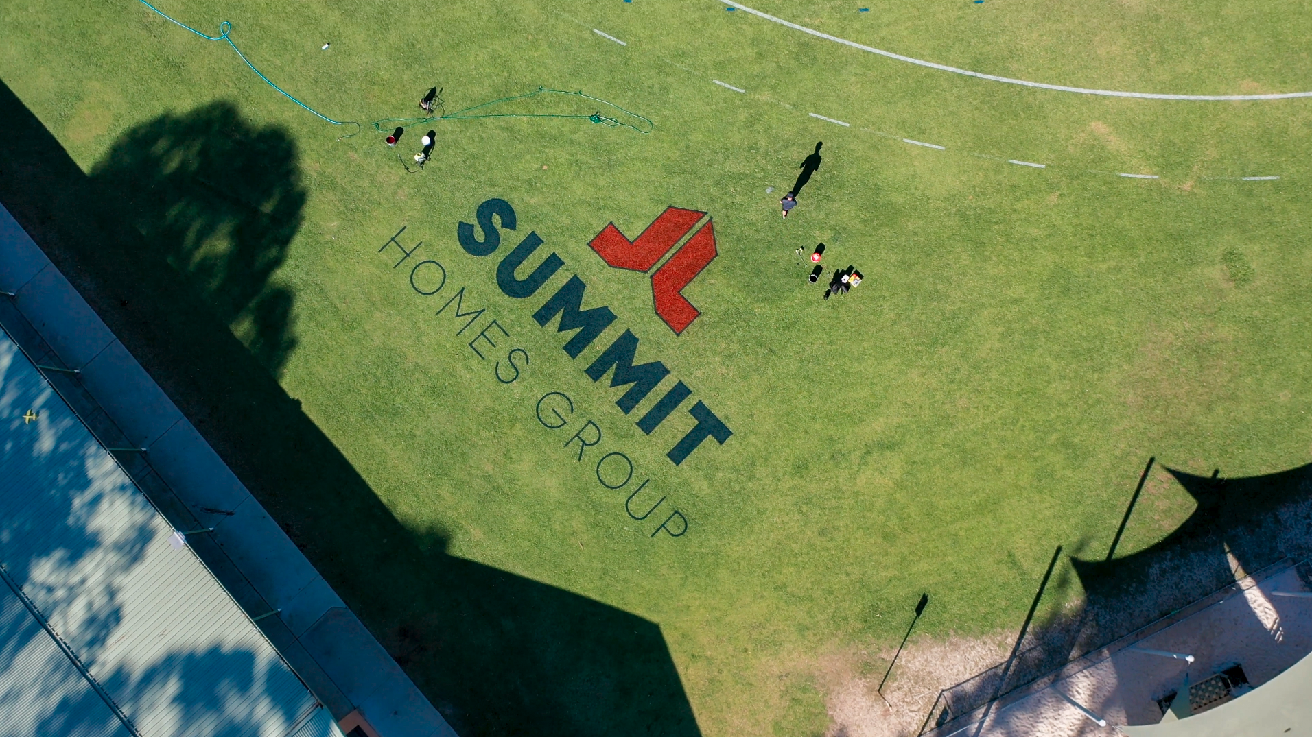 Aerial view of Summit Homes Group logo painted on a grass sports oval