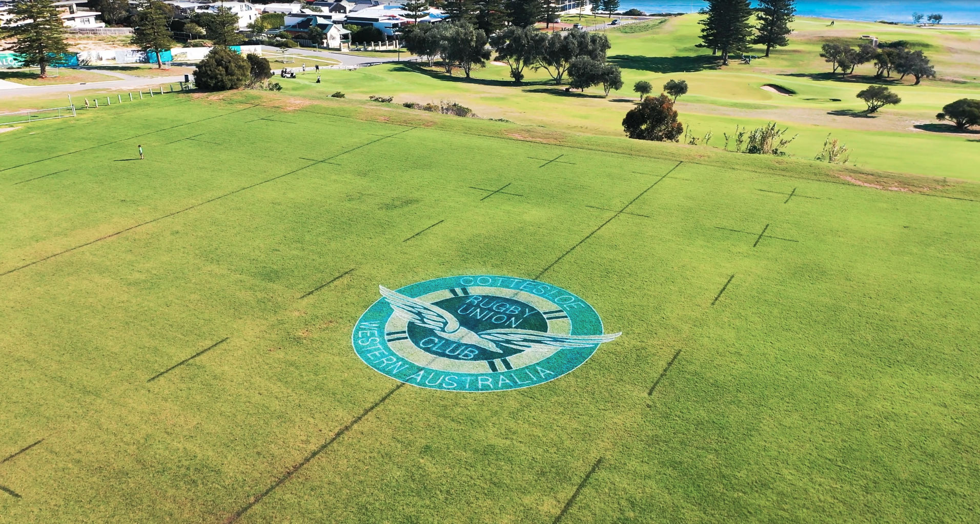 Aerial view of Cottesloe Rugby Union Club logo painted on a grass field near the beach