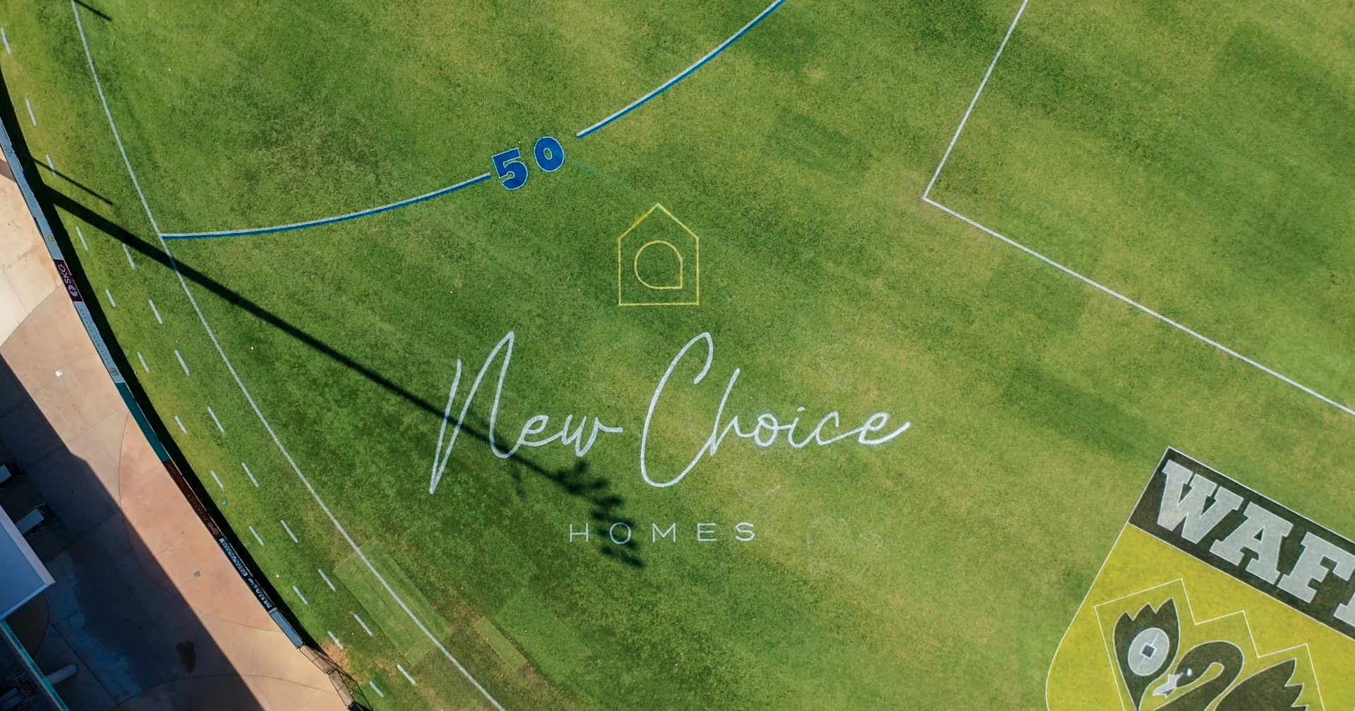 Aerial view of New Choice Homes script logo painted on a WAFL oval