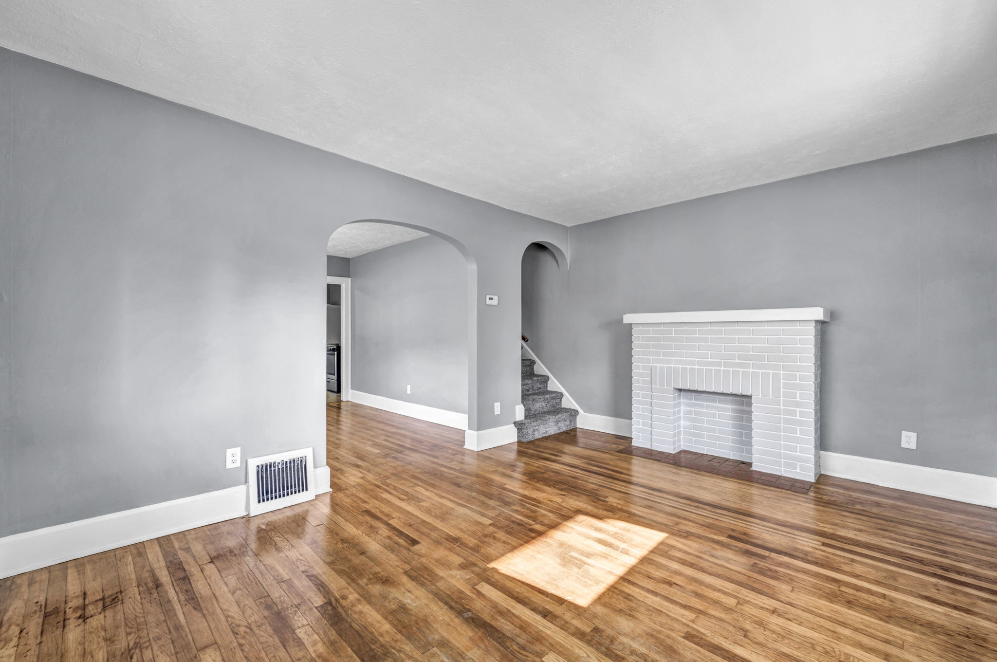 living room photo with hardwood refinished, a fireplace and sunlight hitting the floor