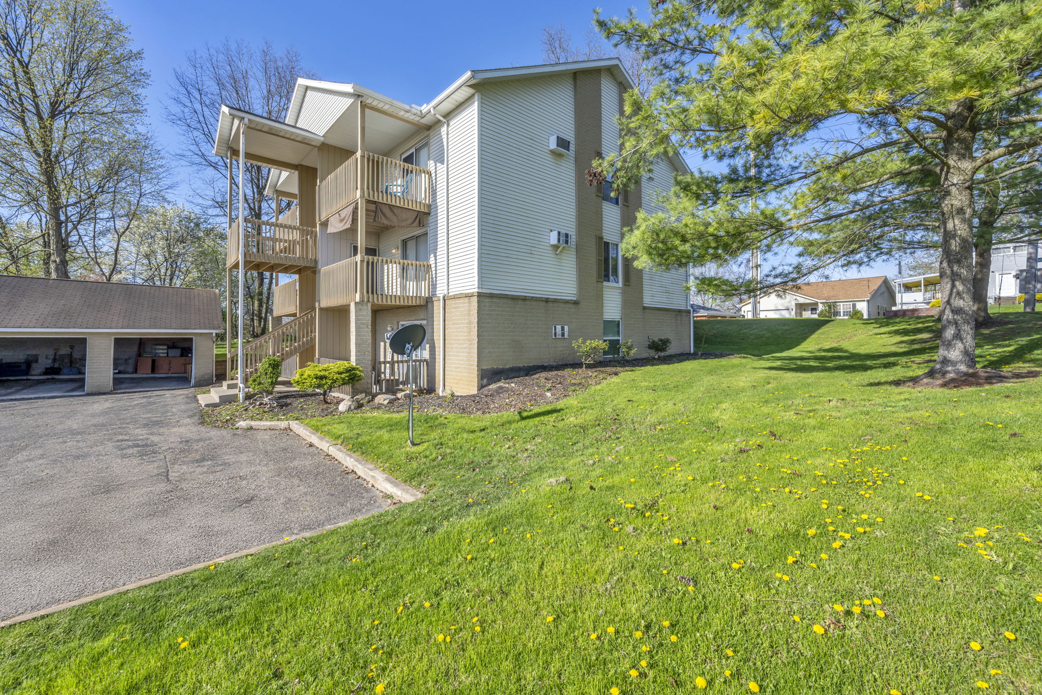 apartment building with grassy yard and partial garage and parking lot next to it