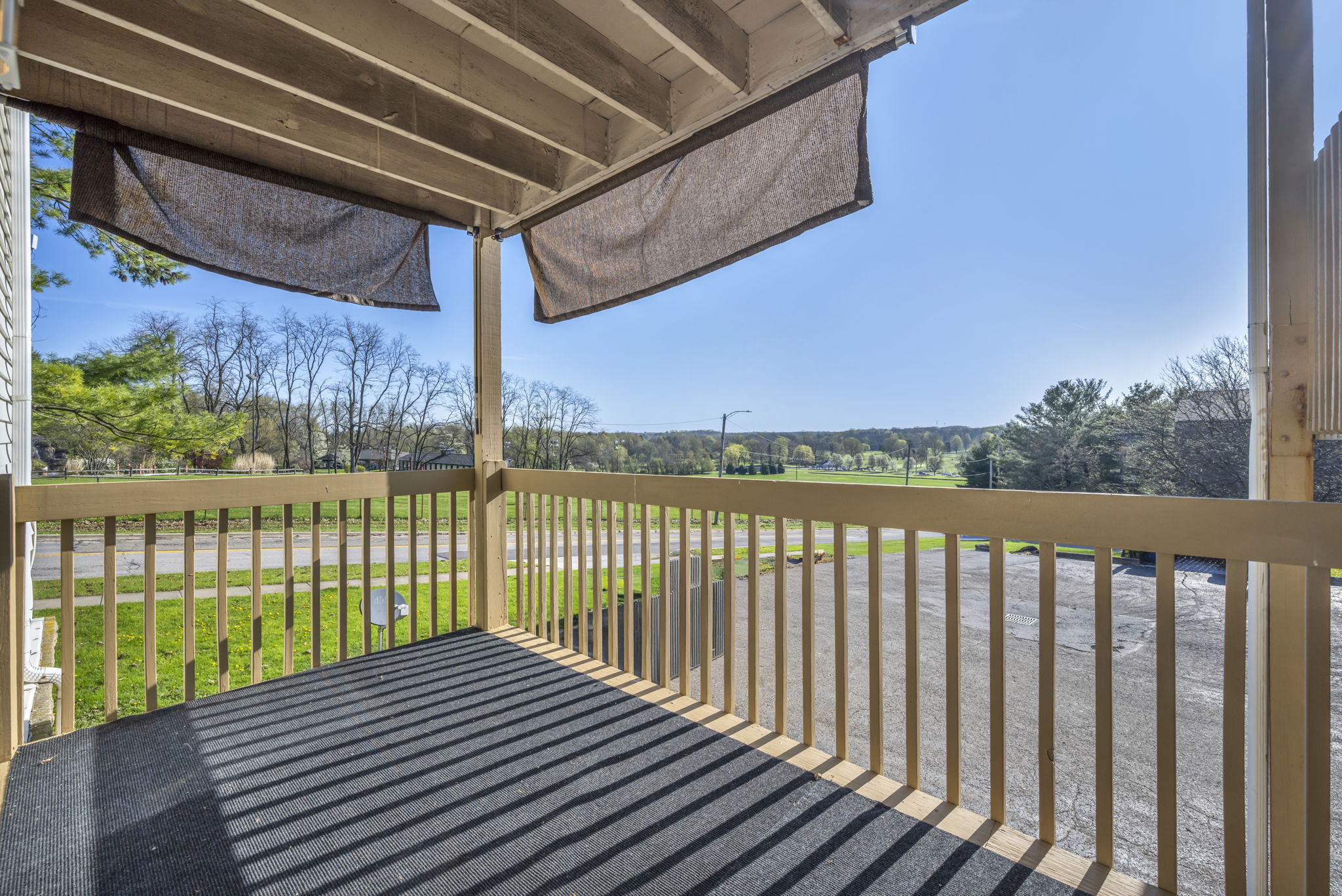 balcony photo with sun rays looking out over a driving range with lots of grass and a sunshade hanging handily