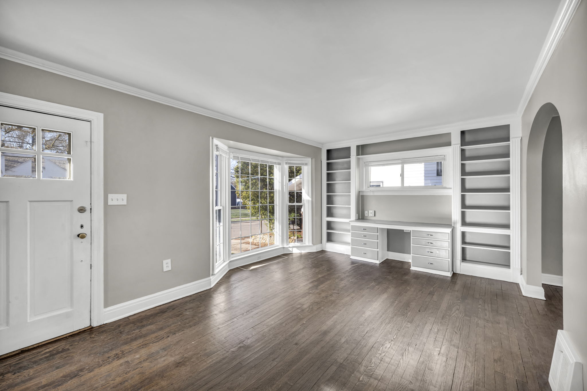 living room photo with brown plank floor, window and built in cabinetry and desk