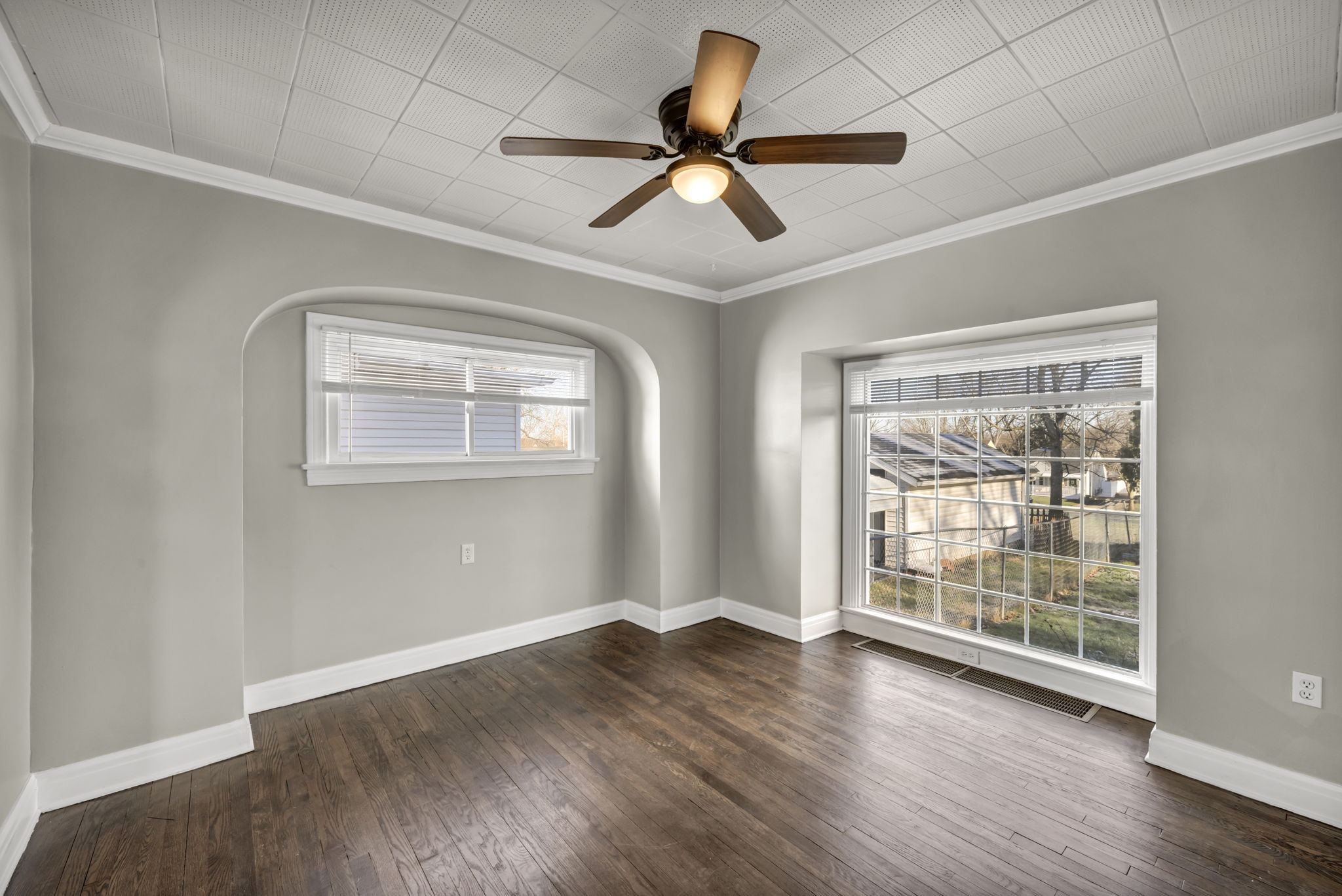 dinning room with beige walls brown plank floor and ceiling fan and large window