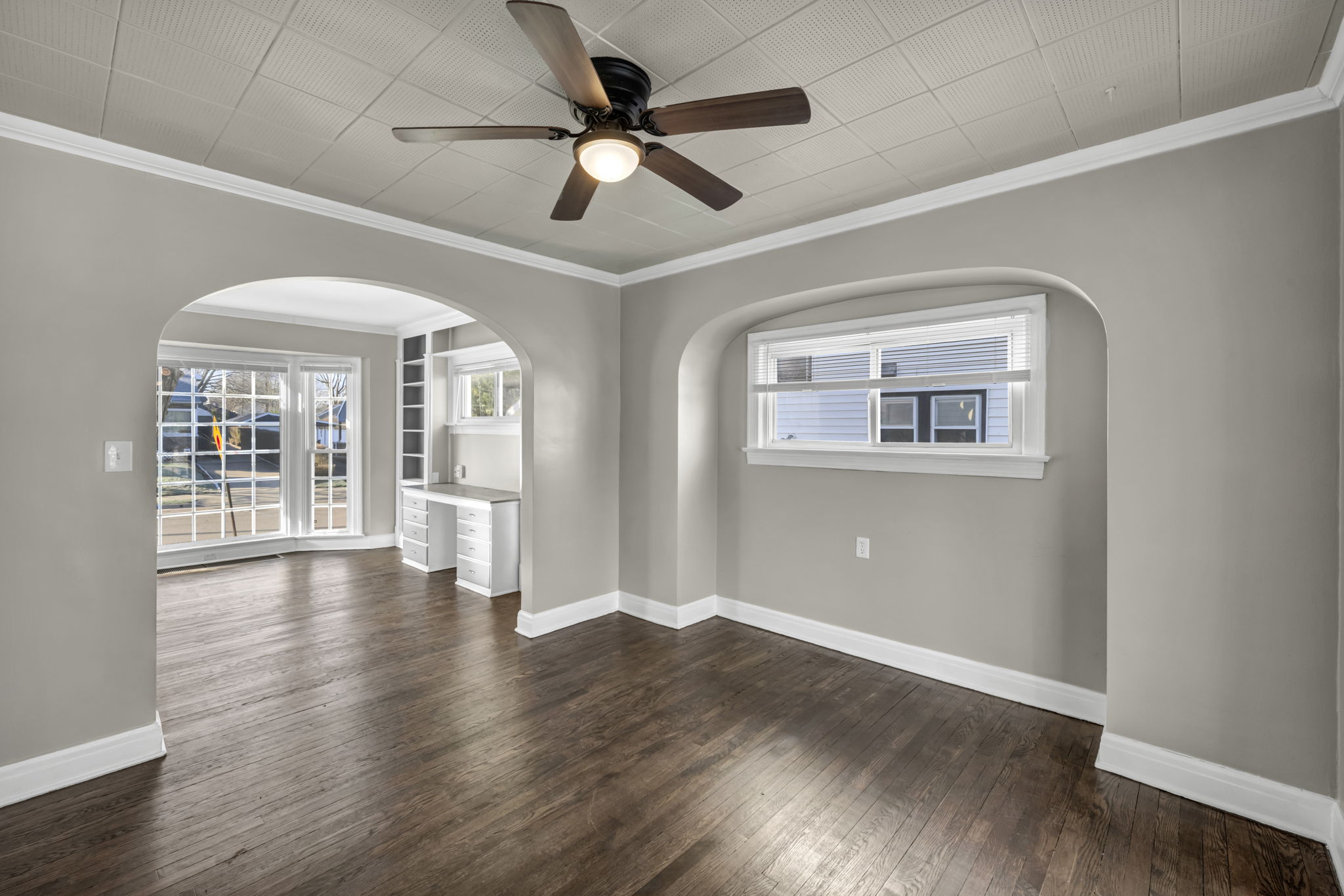 living room and dinning room with beige walls brown plank floor and ceiling fan