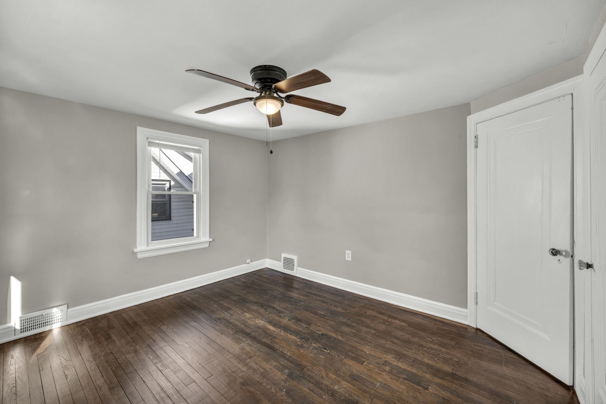 bedroom three with brown hardwood floors a ceiling fan and grey walls