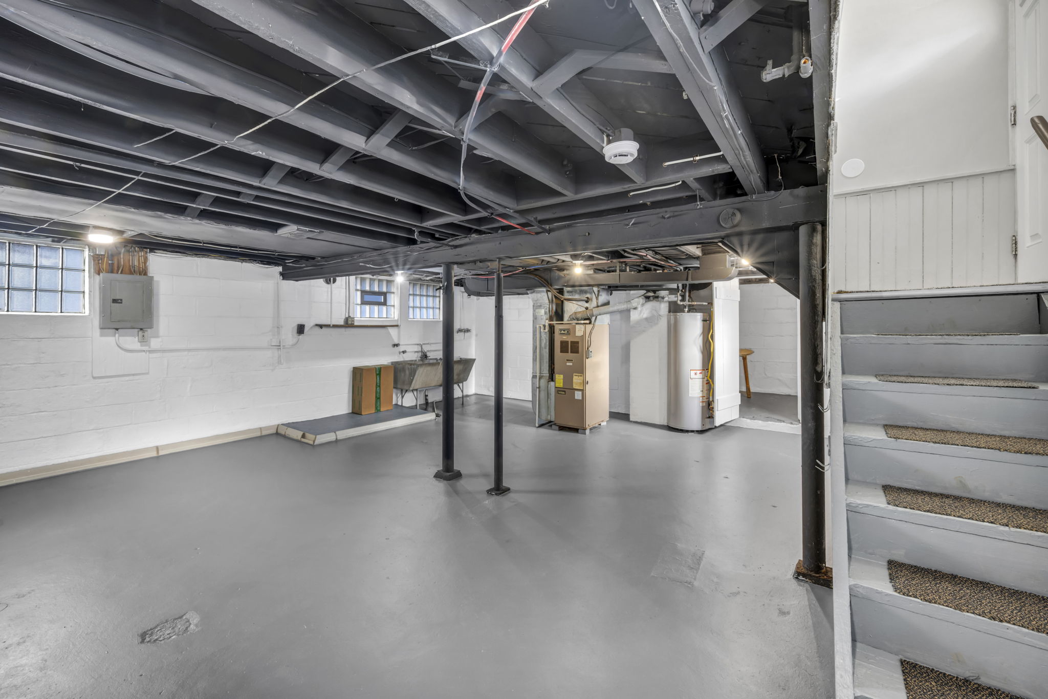 basement painted floors, and painted ceilings with stairs leading up adjacent