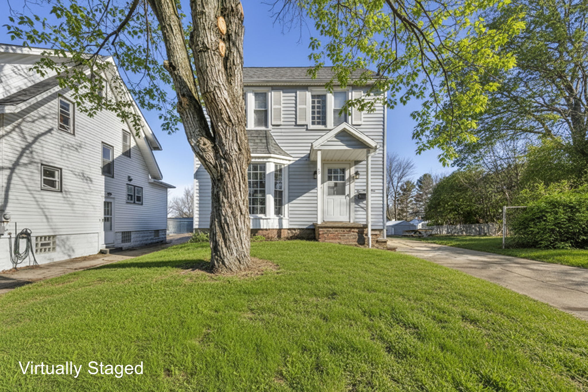 colonial home with front yard and large tree in the yard.