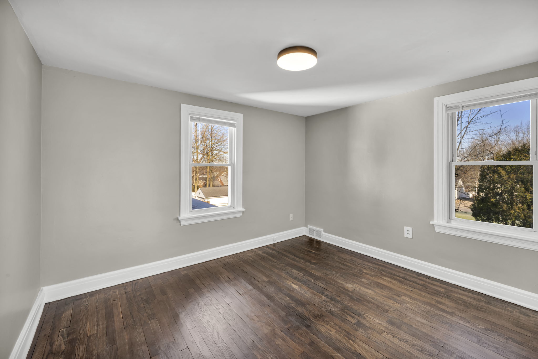 bedroom with hardwood floors, grey walls and two windows