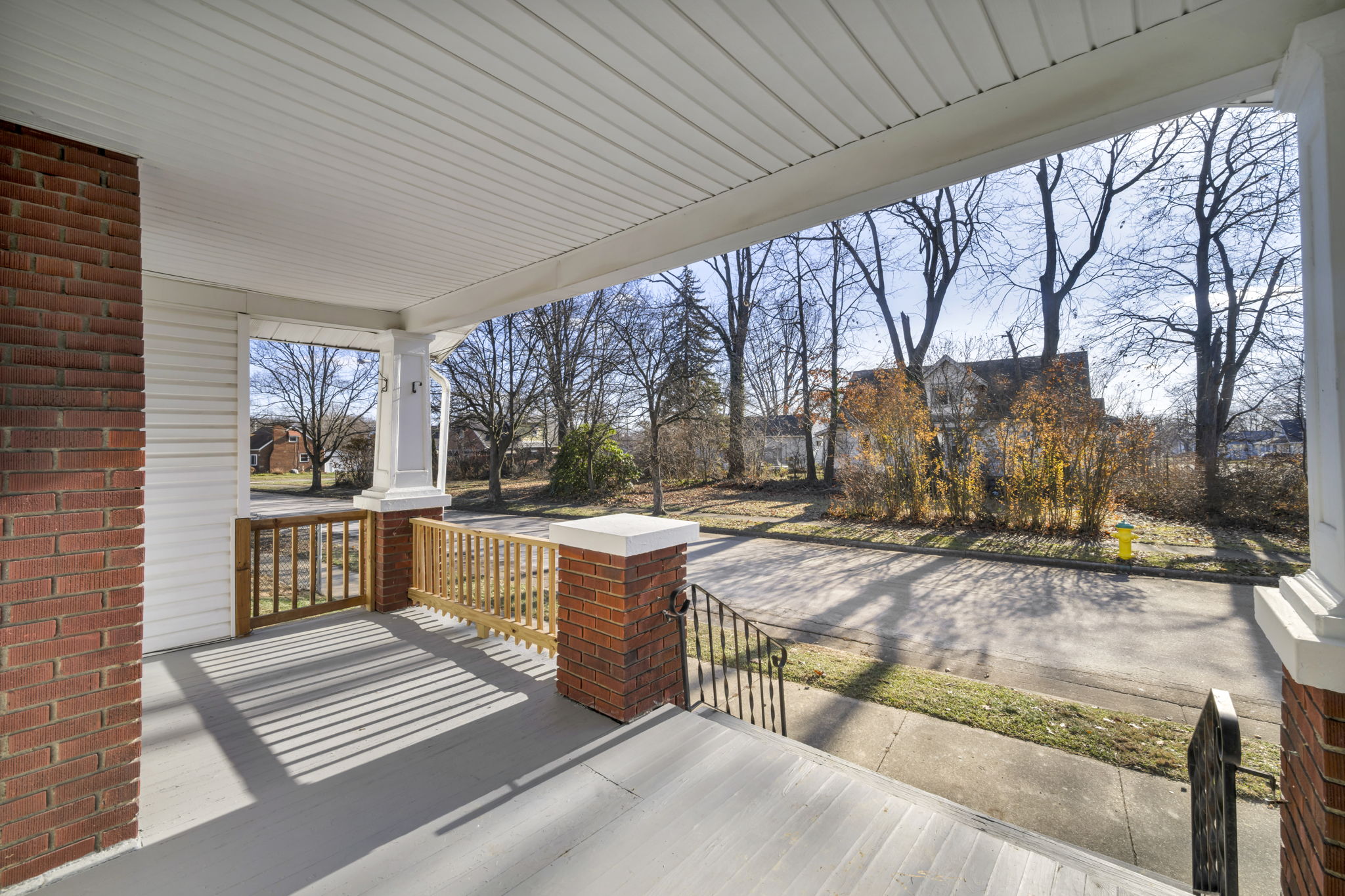 porch photo facing street with brick columns and dead trees