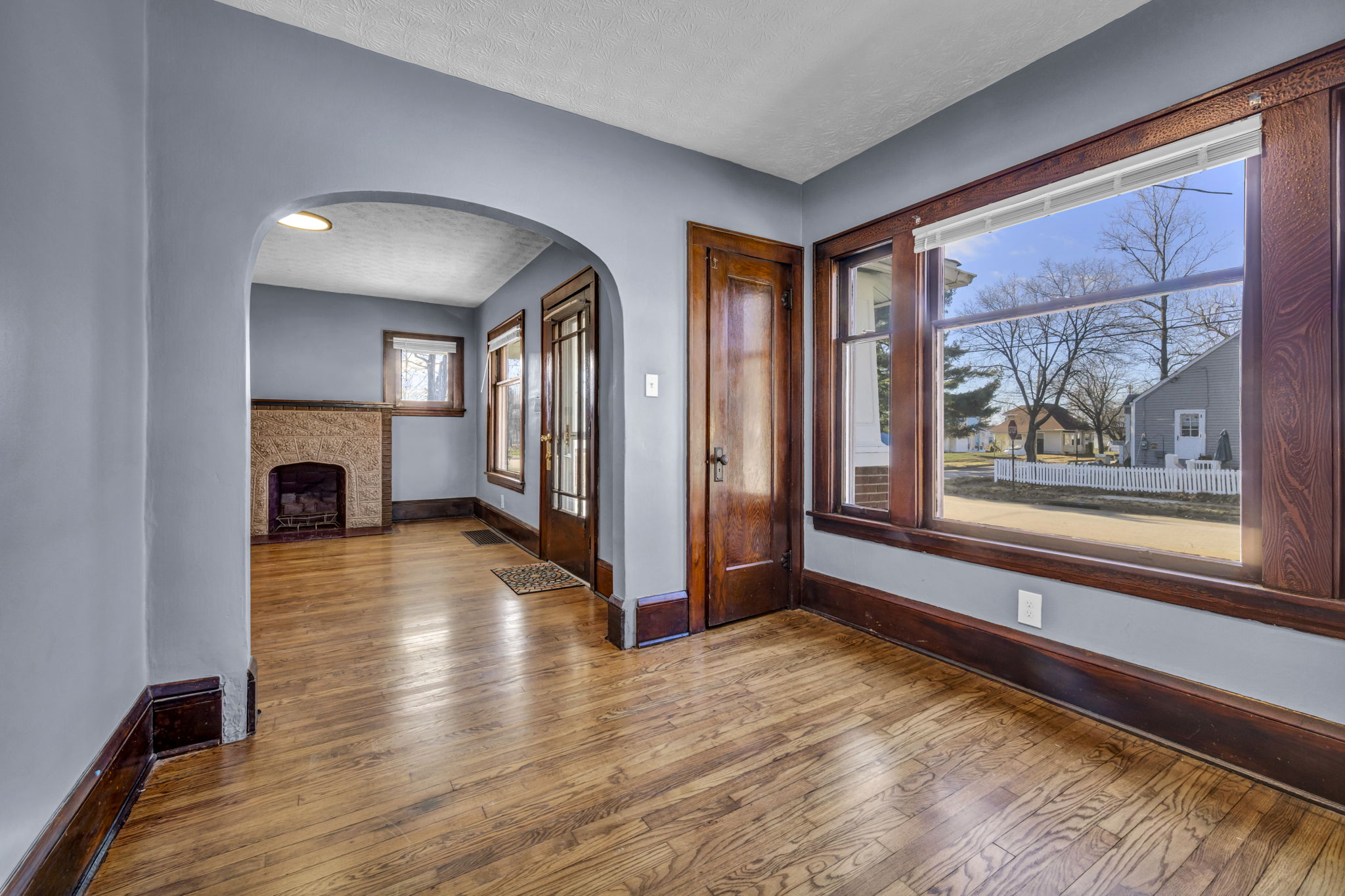 living room with hardwood floor and large window with wood colored trim