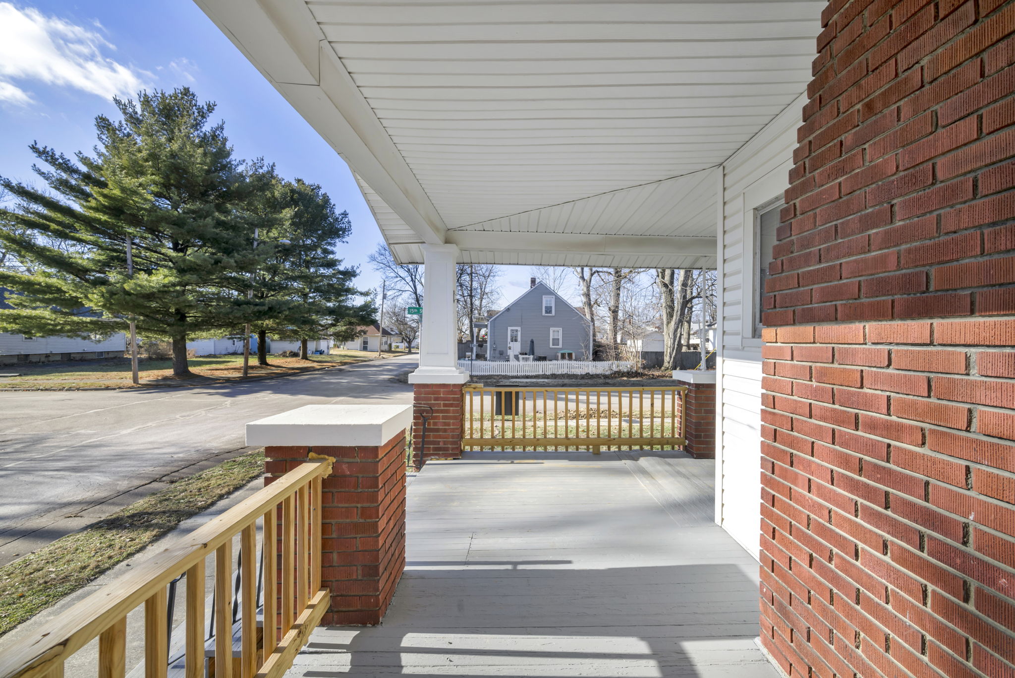 porch photo from on the porch with brick fireplace and cedar tree at street