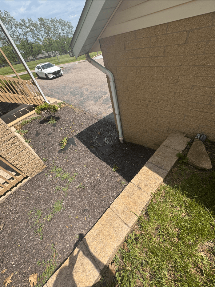 downspout agains garage into pavement, photo from retaining wall of parking looking into parking lot