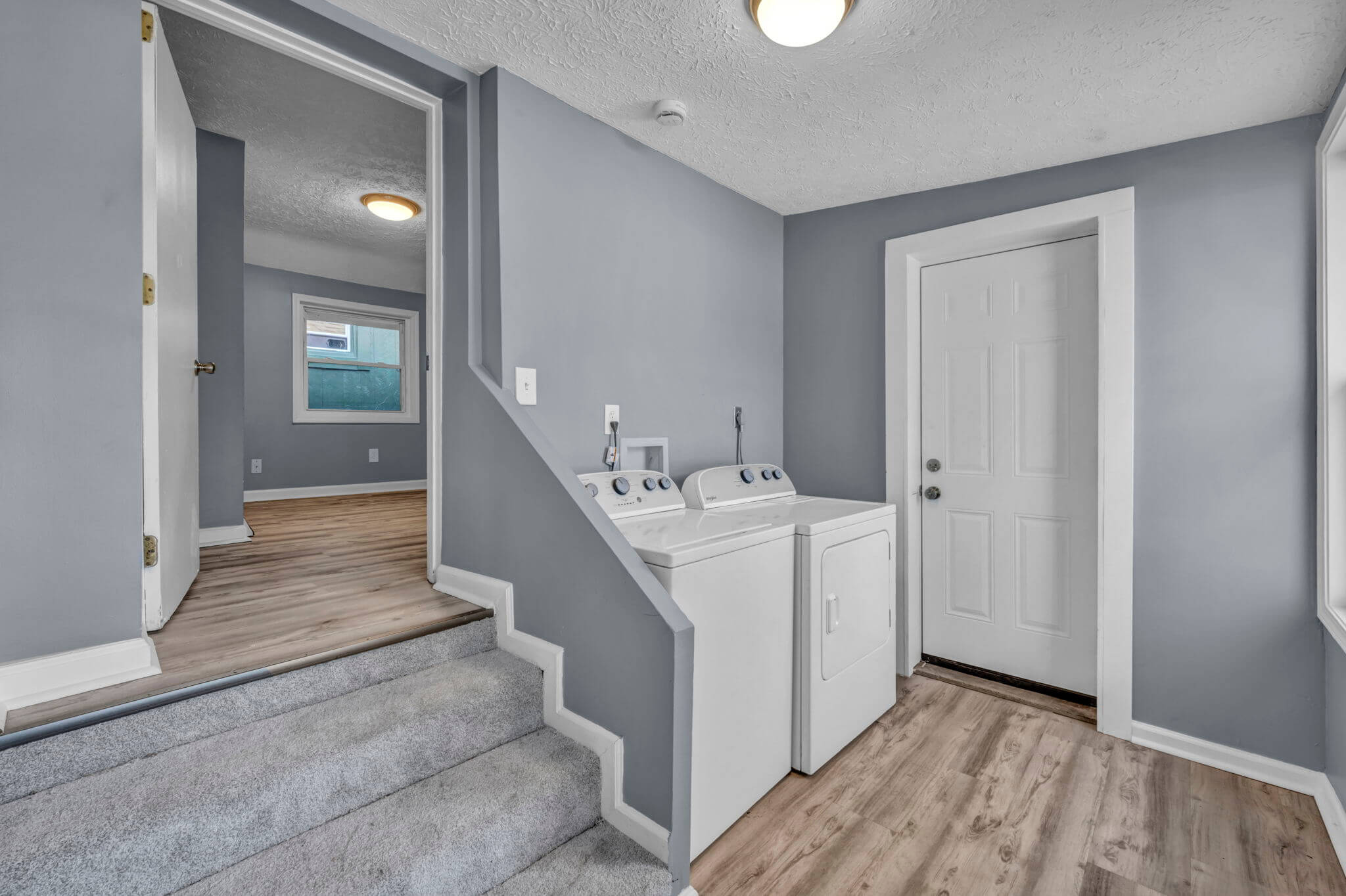 Foyer entrance with washer-Dryer combo grey walls and woodfloor