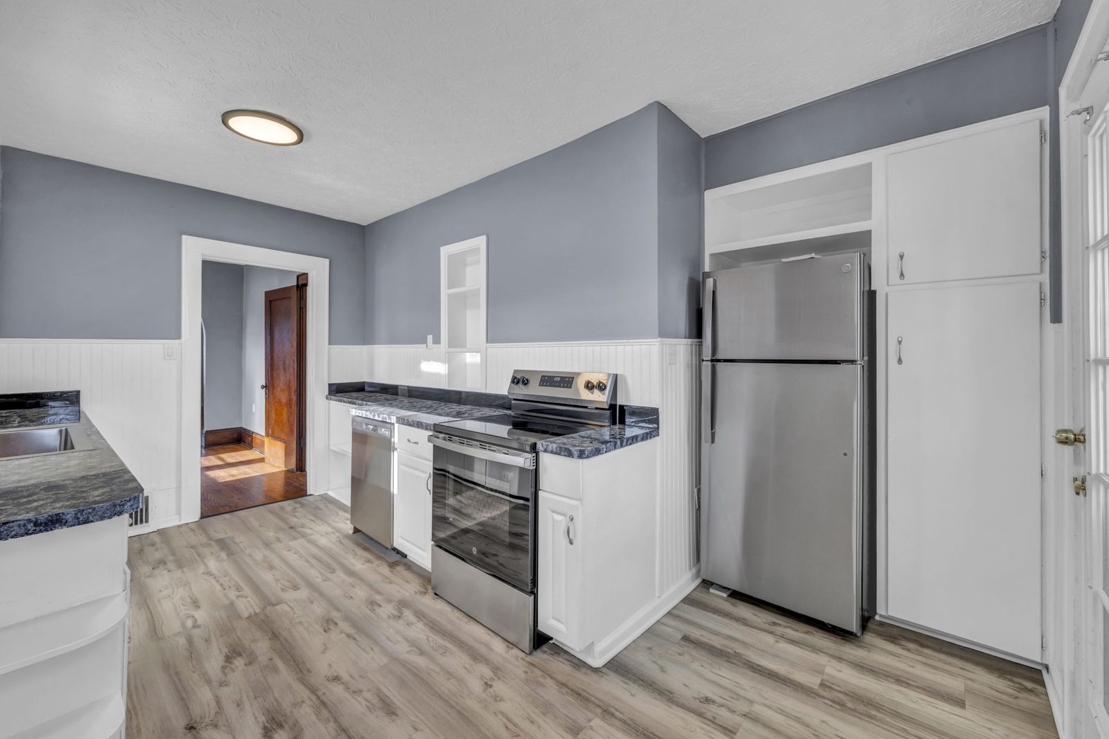 kitchen photo with stainless refrigerator , grey walls and wood floors, dark counter