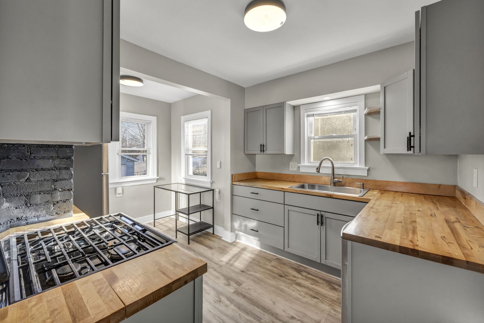 small kitchen with butcher block counters wood floors and grey cabinets with a window and lots of light