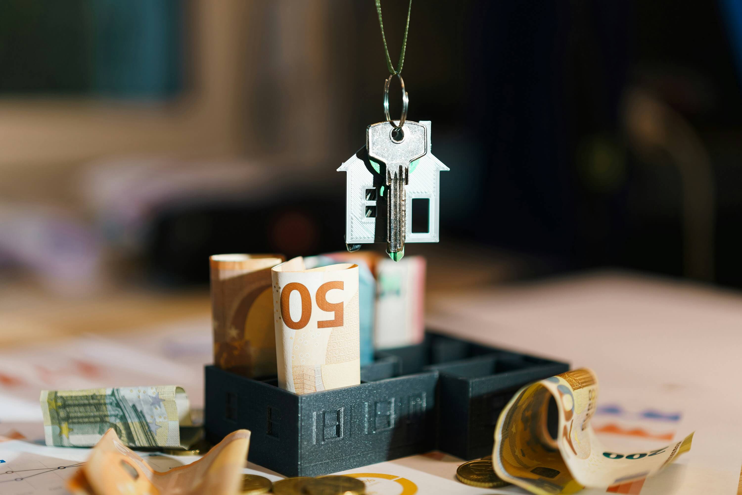 paper currency rolled up with a set of keys hanging above it