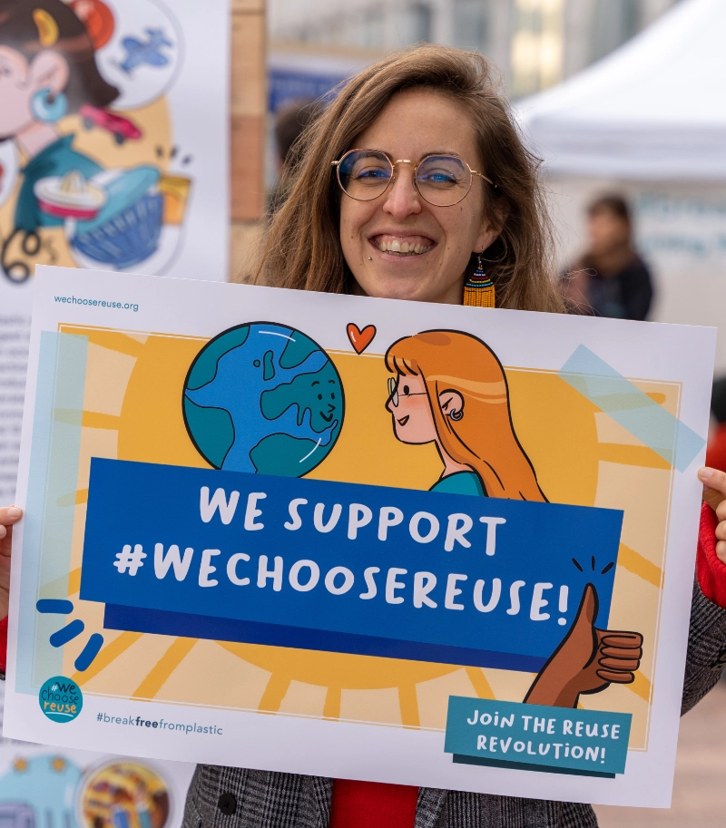 a person holding up a sign that says we choose reuse!