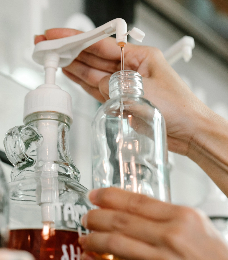 a person refilling a glass bottle