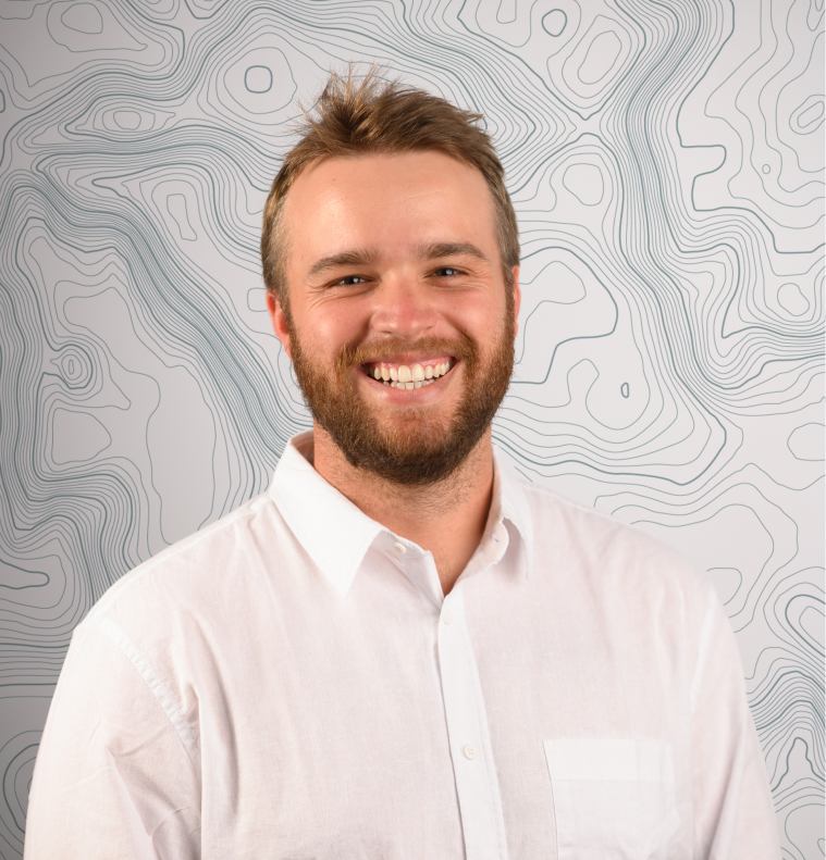 Smiling bearded man in a white button-up shirt with a topographic map pattern background.