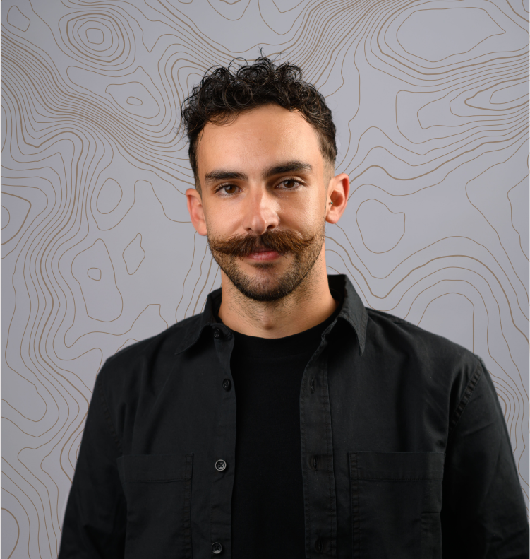 Man with curly hair and a styled mustache wearing a black shirt against a background with contour-style lines.