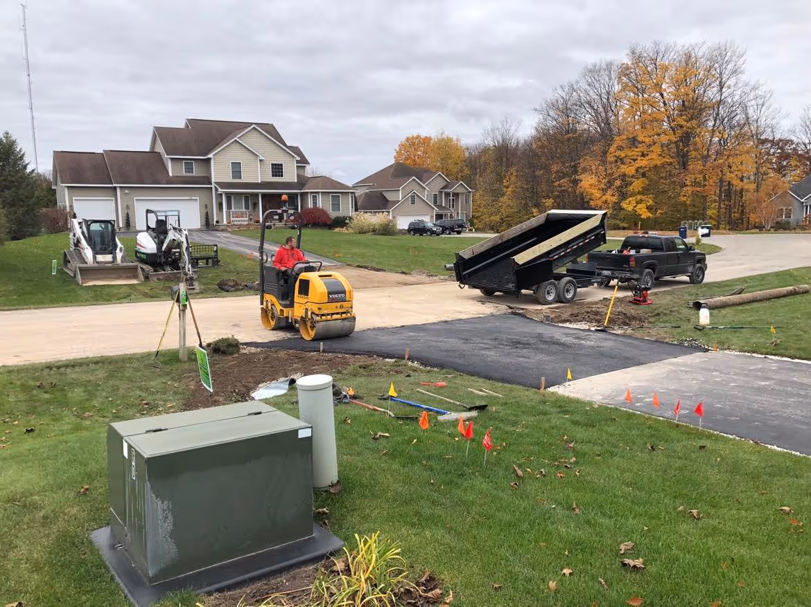 Professional residential driveway asphalt repair in the South Creek subdivision of Traverse City, MI, featuring precision hot-mix compaction.