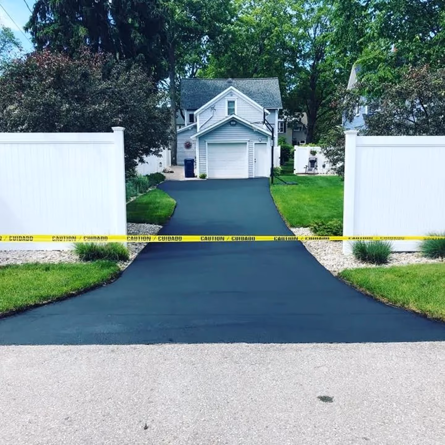 Restored asphalt driveway in Traverse City featuring crisp, hand-brushed edges and a jet-black finish