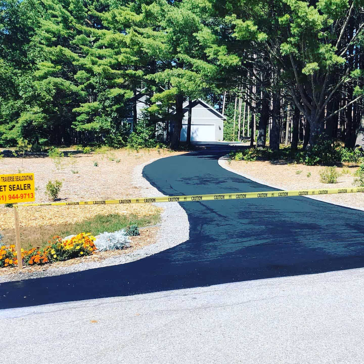 Freshly sealed asphalt driveway in a quiet Glen Arbor neighborhood featuring a jet-black finish.