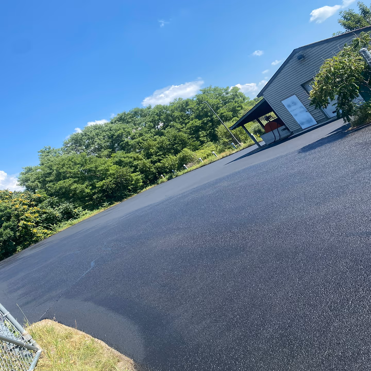Heavy-duty commercial parking lot sealcoating for the Leland Public School Bus Garage on S Popp Rd in Lake Leelanau, MI.
