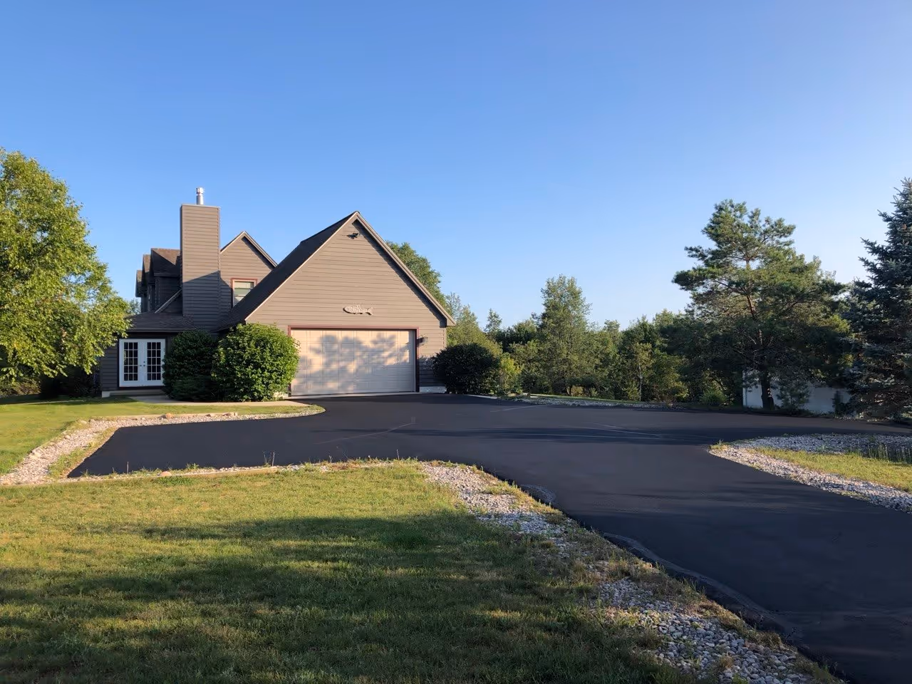 Residential asphalt maintenance and sealcoating for a wooded-lot driveway in the Maple City area.