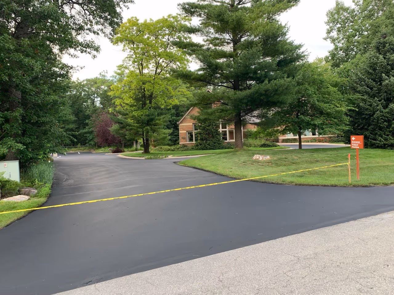Professional commercial parking lot sealcoating for Grand Traverse Ophthalmology on Business Park Dr in Traverse City, MI, featuring a jet-black asphalt finish.