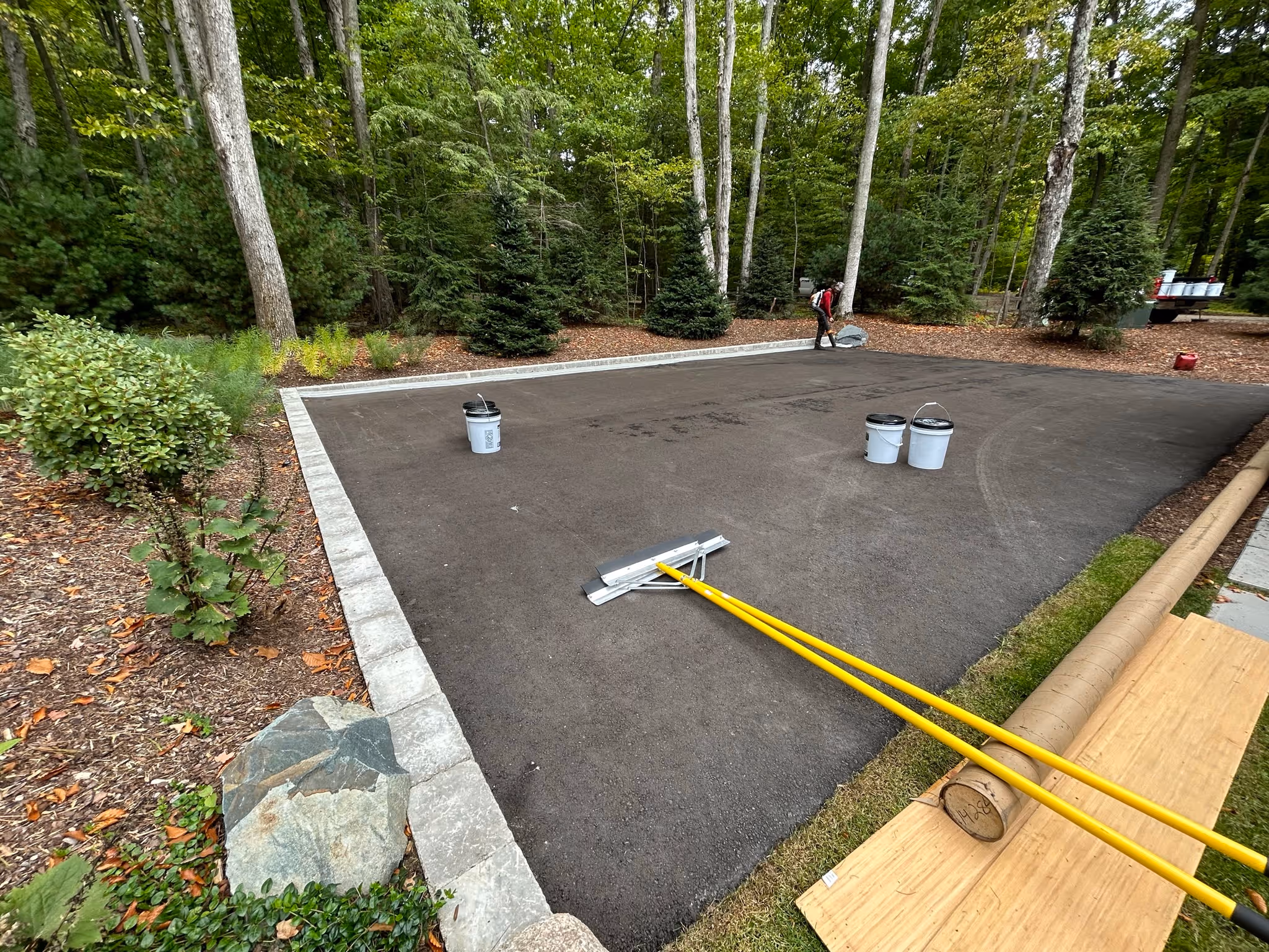 Application of the foundational acrylic resurfacer layer to seal the asphalt and provide a smooth, consistent substrate for the sport court surfacing.