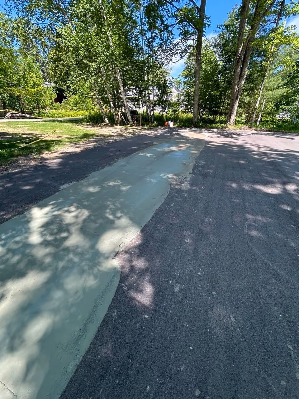 A close-up view of specialized acrylic court patch leveling compound applied over the marked low spots on the Big Glen Lake court. This technical repair ensures a perfectly flat playing surface, eliminating hazardous "birdbaths" before the color surfacing begins.