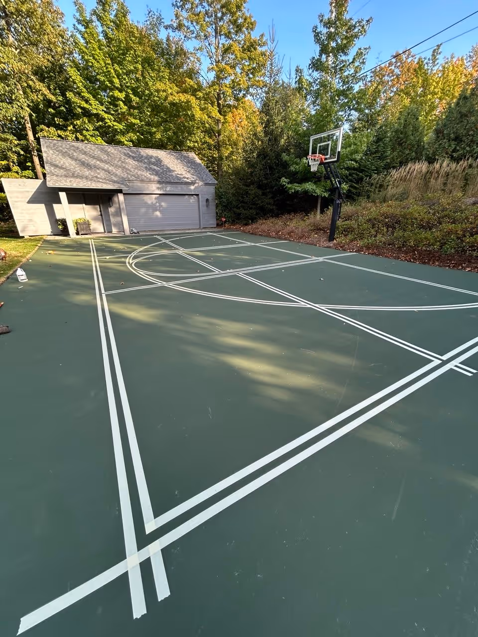 Meticulous hand-taping for the dual-sport layout. This shows the complex organization of pickleball and basketball dimensions on a single green surface.