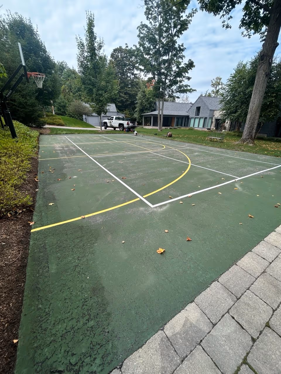 High-pressure washing of the basketball and pickleball court surface in Williamsburg to remove oxidation and debris, ensuring a clean bond for the SportMaster system.