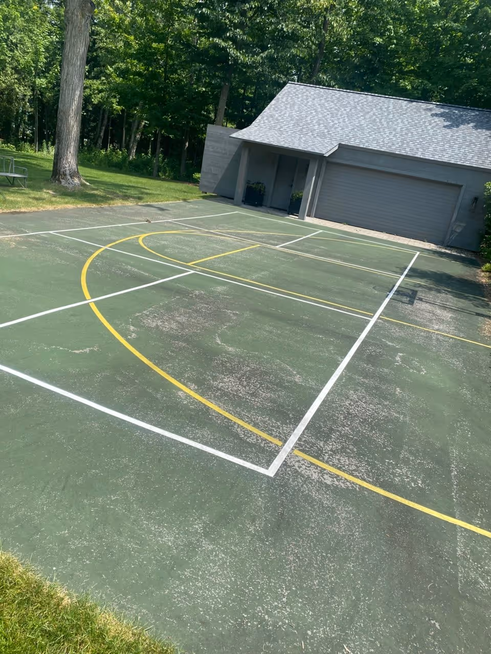 The original, faded condition of a private residential multi-sport court on S Shore Dr in Williamsburg, MI, before the professional resurfacing process began.