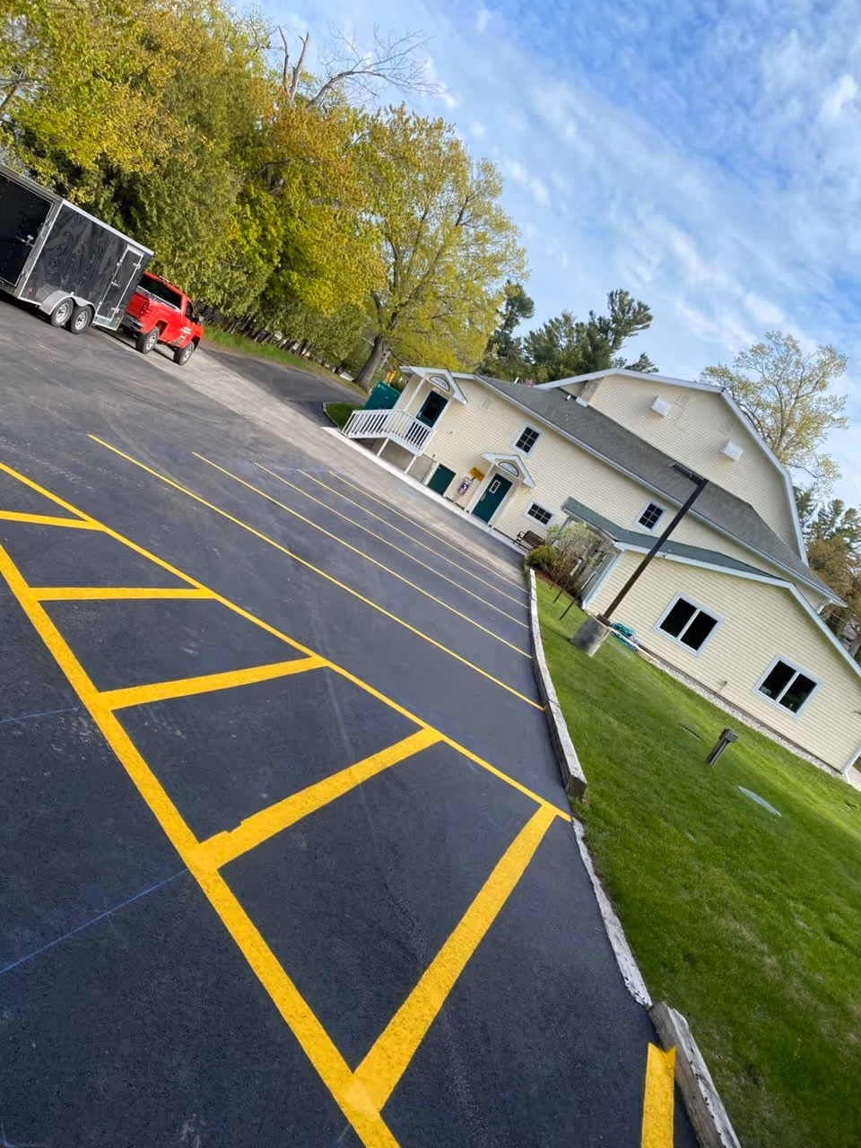 A newly paved asphalt parking lot at the Glen Arbor Township Hall on Western Ave in Glen Arbor, MI. The image showcases a precision-engineered new layout and vibrant white line striping completed for Team Elmer's, providing clear organization and professional pavement markings for the municipal facility.