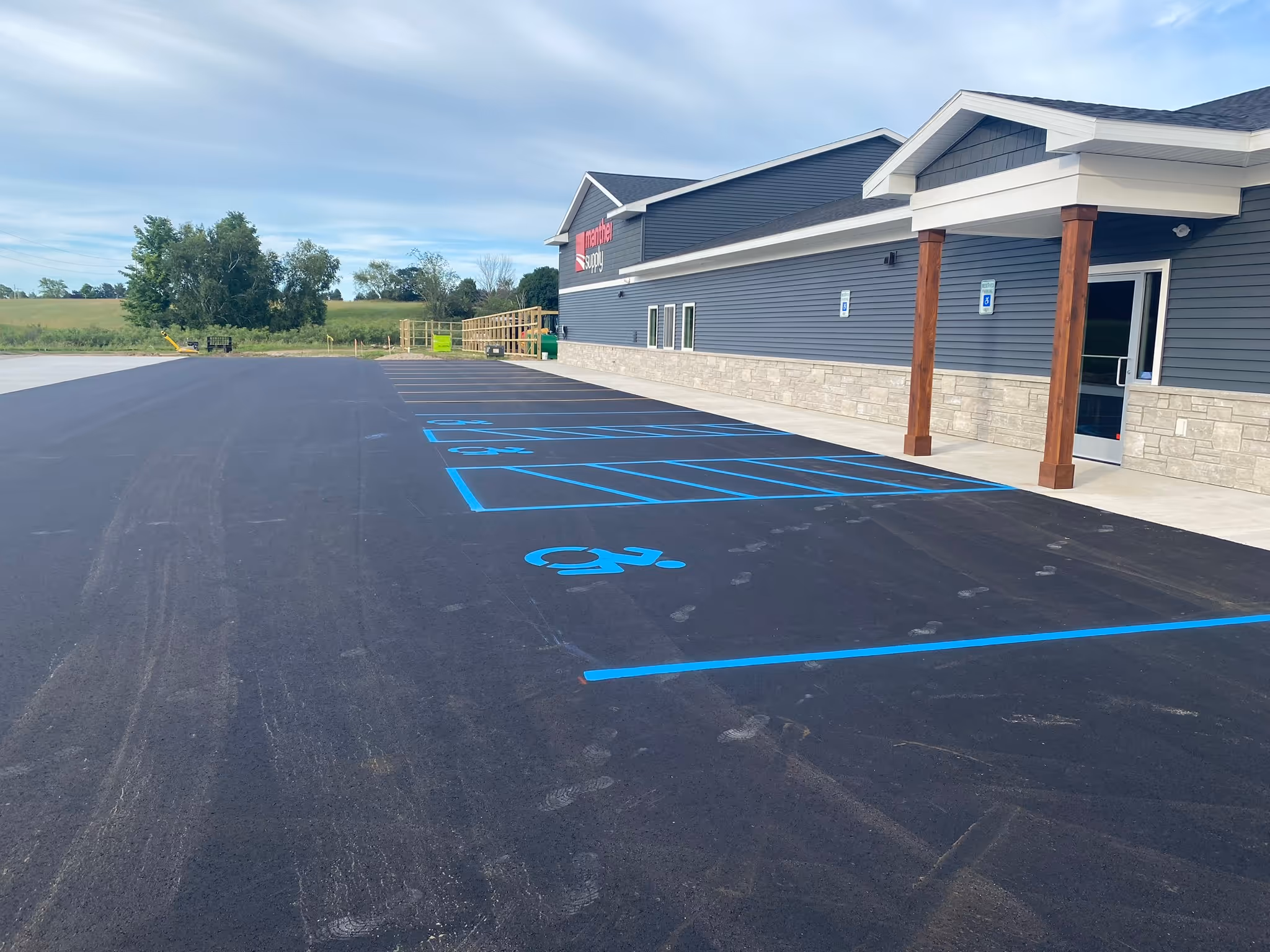 A comprehensive new parking lot layout and precision line striping at Manthei Supply on the corner of Sawyer and US-31 S in Traverse City, MI. This commercial project, completed for Team Elmer's, showcases high-visibility white pavement markings designed for heavy-duty industrial traffic and customer organization.