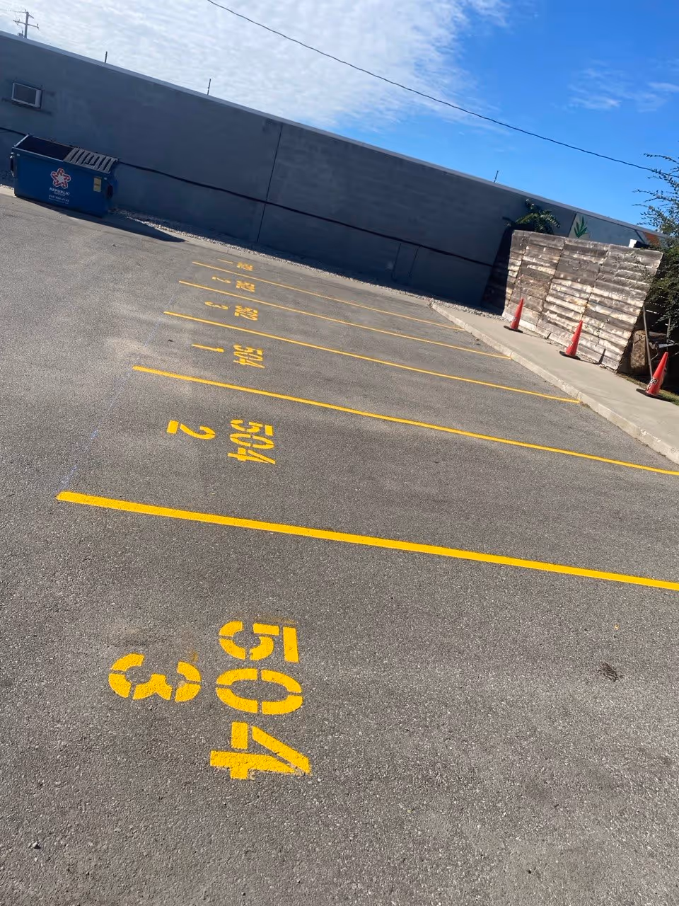 Professional parking lot restriping and custom stall numbering at a multi-family apartment complex in Traverse City, MI. The image features crisp white lines and precision-stenciled numbers, providing organized assigned parking and enhanced property management for local residents.