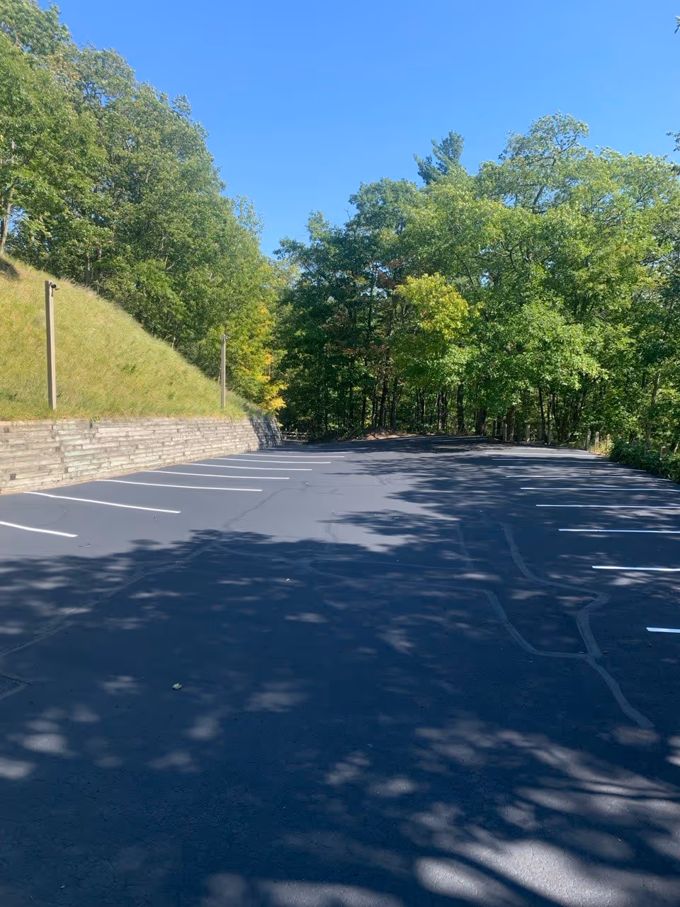 The completed parking lot restoration project at The Homestead Resort's Pinnacle Place in Glen Arbor, MI. The upper parking area shows finished asphalt patching, professional sealcoating, and fresh white parking lines, delivering a premium turn-key solution on the M-22 Scenic Byway corridor.