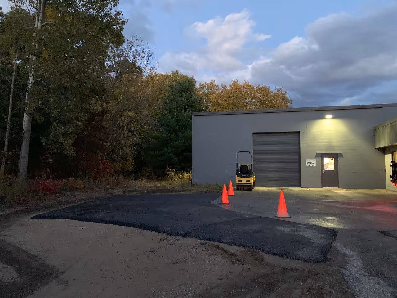 The completed parking lot extension at Threads Custom Gear off Cass Rd. The finished asphalt surface provides a durable area for the delivery truck loading zone and service door, enhancing the facility's logistical efficiency.