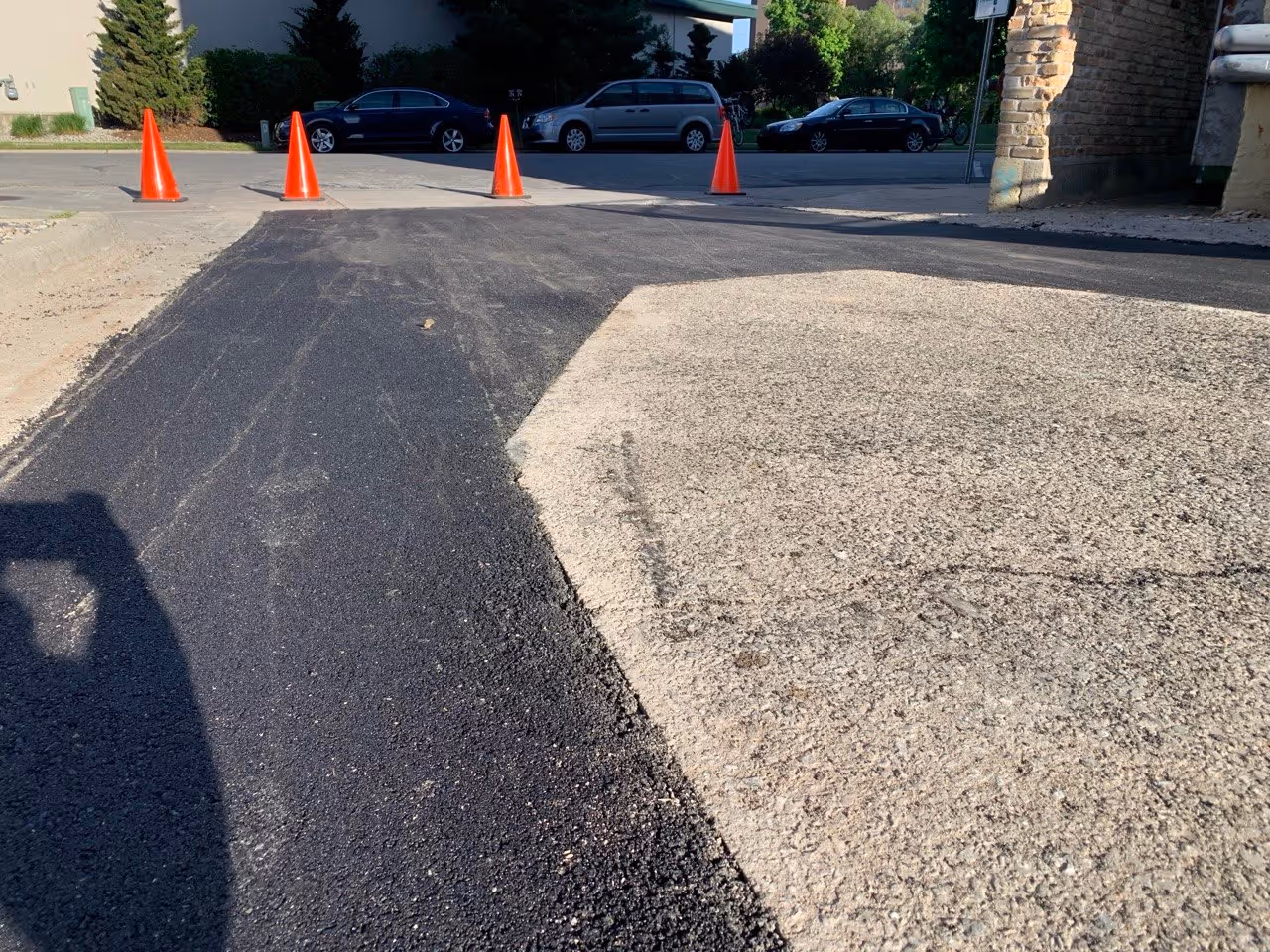 A close-up view of a smooth, professionally finished asphalt patch at a commercial parking lot entrance in Traverse City. The high-quality surface restoration ensures a seamless transition for clients visiting Eternal Wellness Medical Spa.
